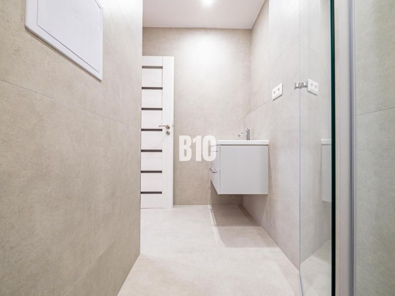 Badezimmer in einer 3-Zimmer-Wohnung mit einfachem Design und einem hängenden Waschbecken.