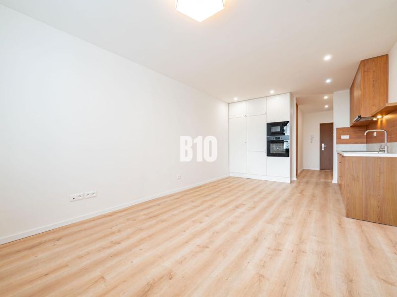 Helle Küche mit weißen Schränken, Holzboden in einer 3-Zimmer-Wohnung.