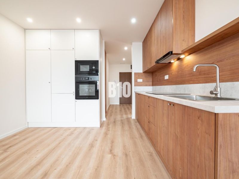 Küche in einer 3-Zimmer-Wohnung mit weißen Schränken und einem Boden in Holzoptik.