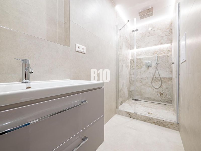 Badezimmer in einer 3-Zimmer-Wohnung mit moderner Duschkabine und Waschbecken.