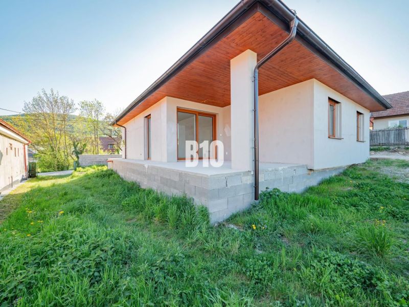 Ein Einfamilienhaus in Nitra mit einer Betonterrasse und einem grünen Rasen im Garten.