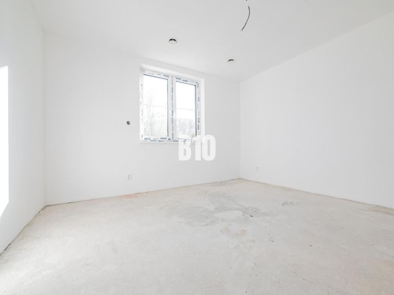 Ein leerer Raum mit weißen Wänden und Betonboden in einem Einfamilienhaus.