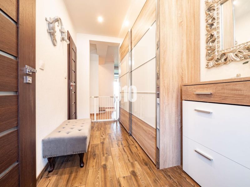 Flur mit Holzboden, Schränken und Spiegel in einem Einfamilienhaus.