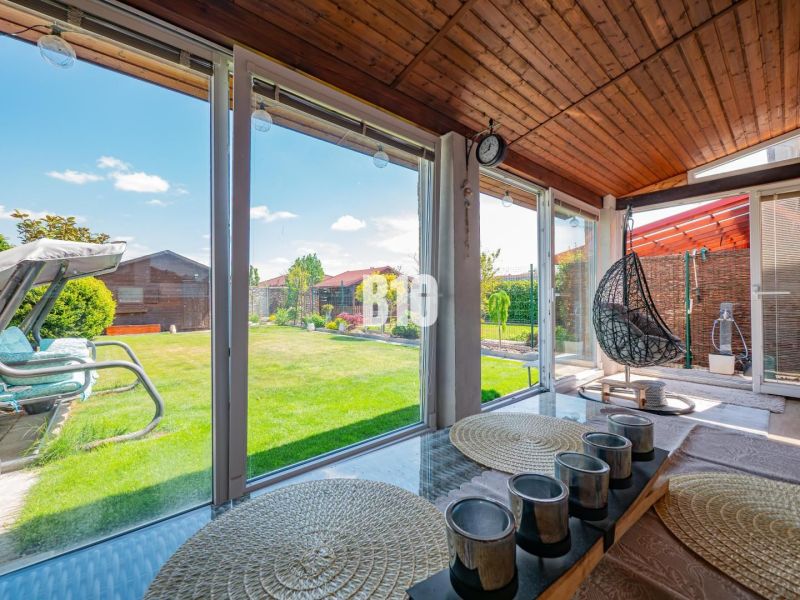 Eine verglaste Terrasse eines Einfamilienhauses in Nitra mit Blick auf den Garten und Holzelementen.