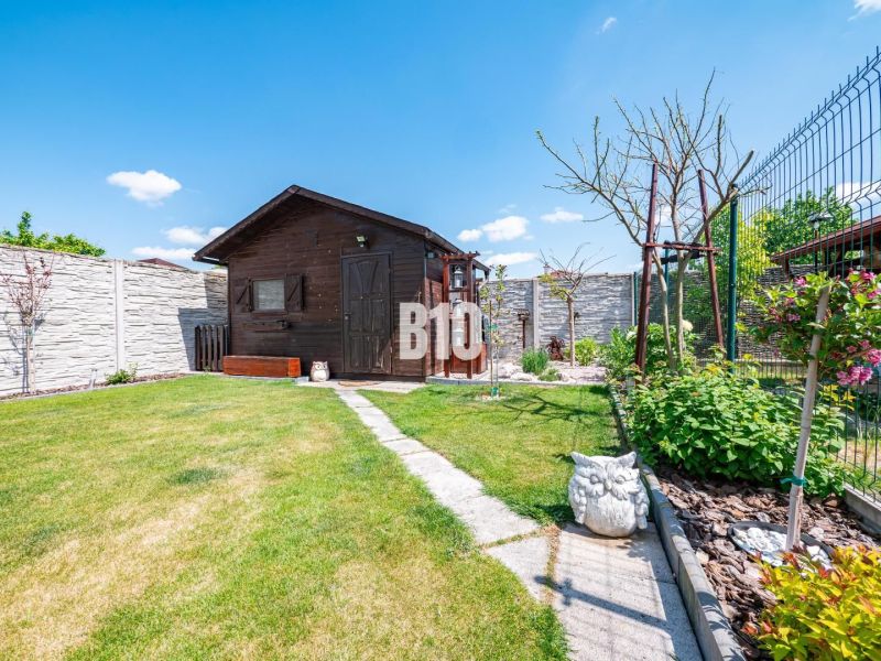 Der Garten eines Einfamilienhauses in Nitra mit einem Gartenhäuschen, grünem Rasen und Dekorationen.
