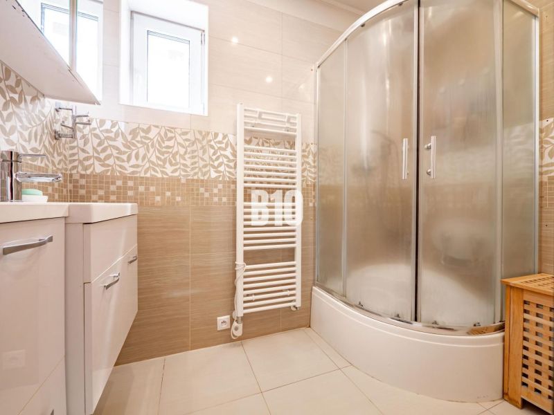 Badezimmer in einem Einfamilienhaus mit einer Eckdusche und hellen Fliesen.