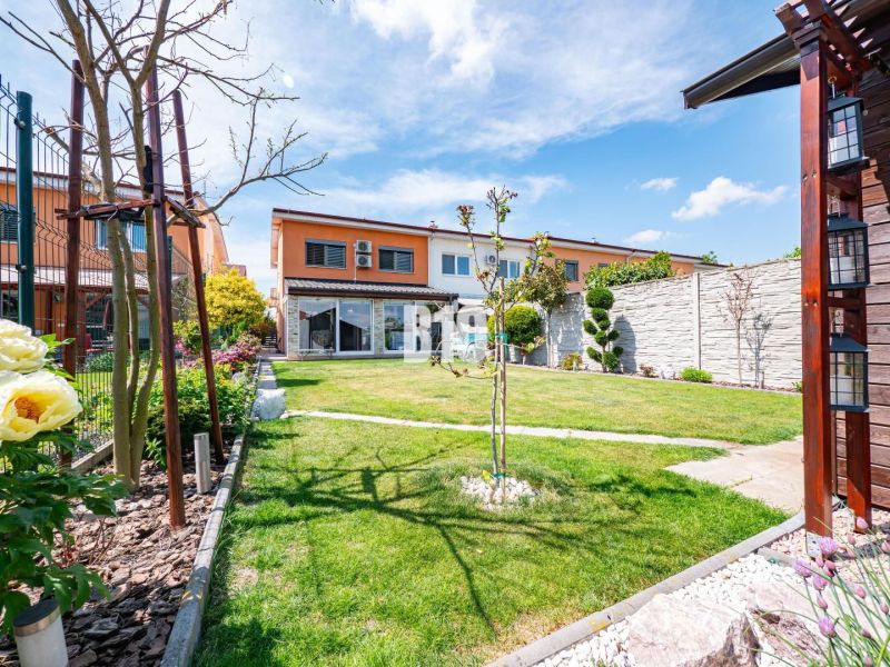 Ein Garten bei einem Einfamilienhaus in Nitra mit Rasen, Blumen und Terrasse.