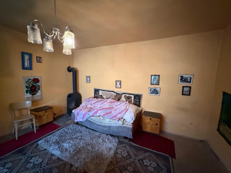 Ein Schlafzimmer in einem Einfamilienhaus mit Kachelofen, Bett und dekorativen Bildern an der Wand.