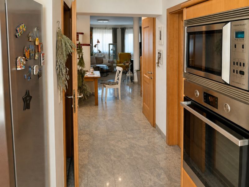 Moderne Küche mit Edelstahlgeräten, offener Blick ins Wohnzimmer in einem Einfamilienhaus.