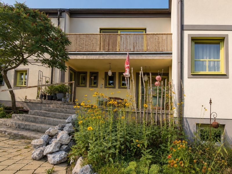 Ein Einfamilienhaus in Podersdorf am See mit Steintreppen und einem Garten voller Blumen.