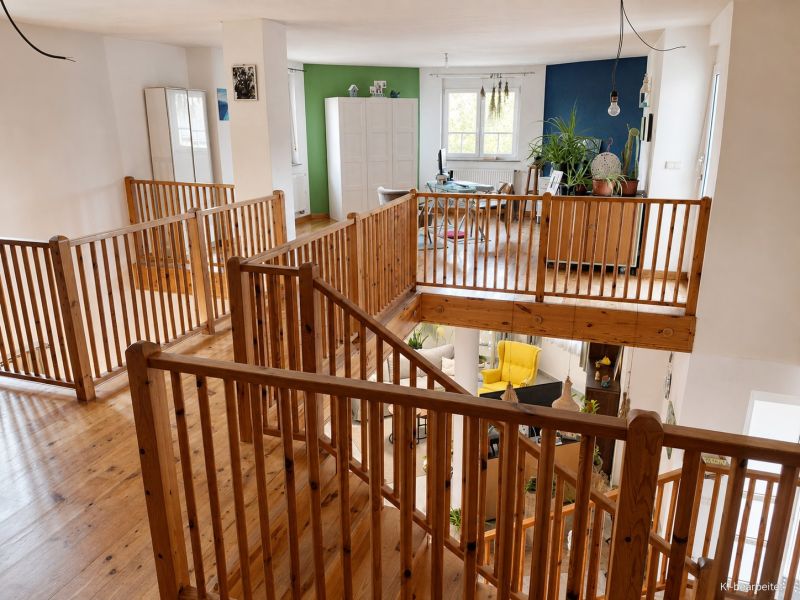 Innenraum eines Einfamilienhauses mit Holzboden und Holzgeländer.