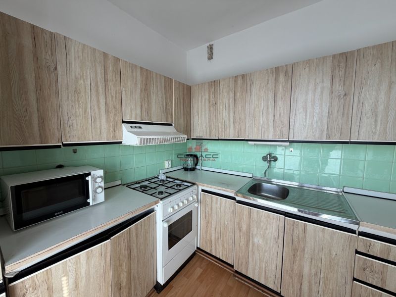 Küche in einer 3-Zimmer-Wohnung mit Holzboden und Holzschränken.