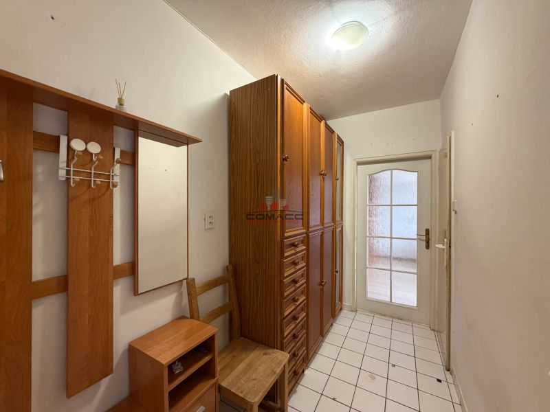 Der Flur in der 3-Zimmer-Wohnung mit Holzelementen und Fliesenboden.