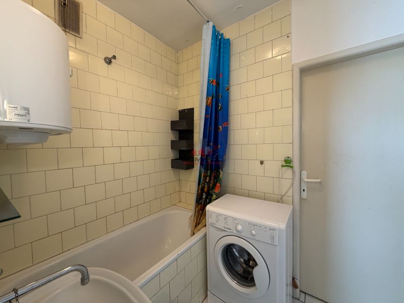 Badezimmer in einer 3-Zimmer-Wohnung mit Badewanne, Waschmaschine und weißen Fliesen.