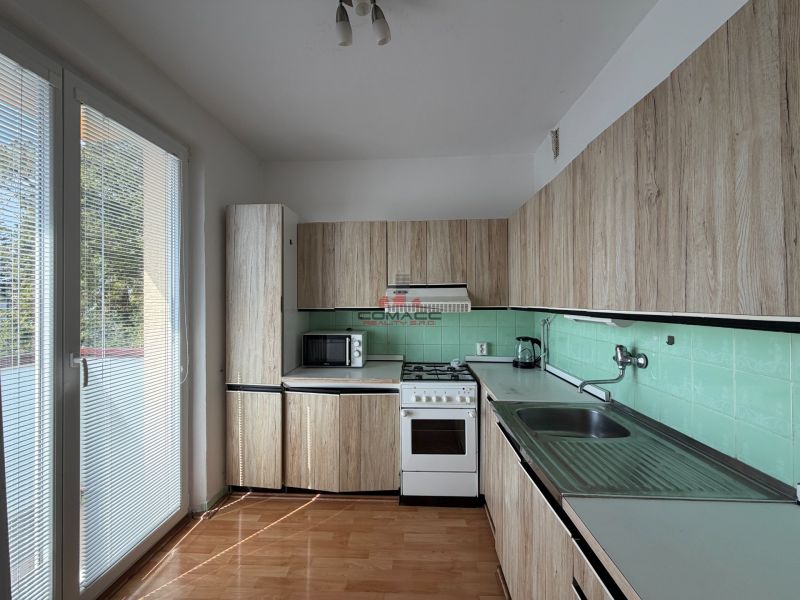 Küche in einer 3-Zimmer-Wohnung mit Holzboden und direktem Zugang zum Balkon.