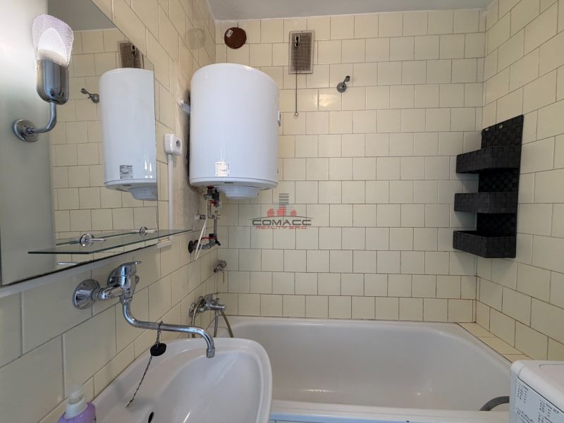 Badezimmer in einer 3-Zimmer-Wohnung mit Badewanne, Waschbecken und Wassererhitzer.