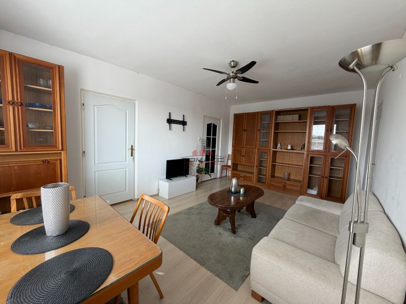 Wohnzimmer einer 3-Zimmer-Wohnung mit Holzmöbeln und einem Boden in Holzoptik.