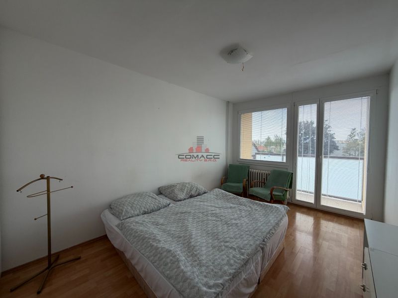Schlafzimmer in einer 3-Zimmer-Wohnung mit Holzboden, Bett und Sesseln.