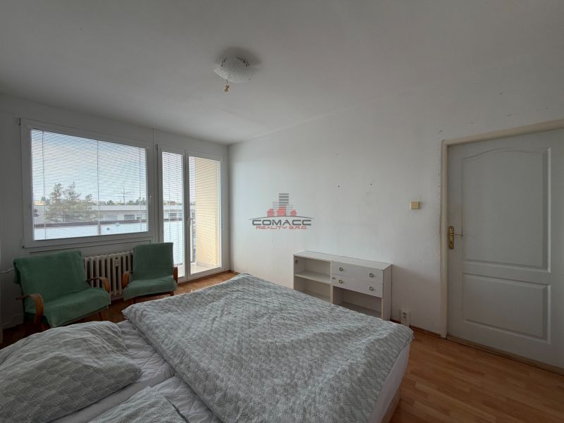 Schlafzimmer in einer 3-Zimmer-Wohnung mit Holzboden, Bett und Sesseln.