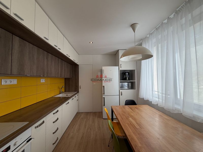 Eine Küche mit Holzboden, gelben Fliesen und einem Esstisch in einer 3-Zimmer-Wohnung.