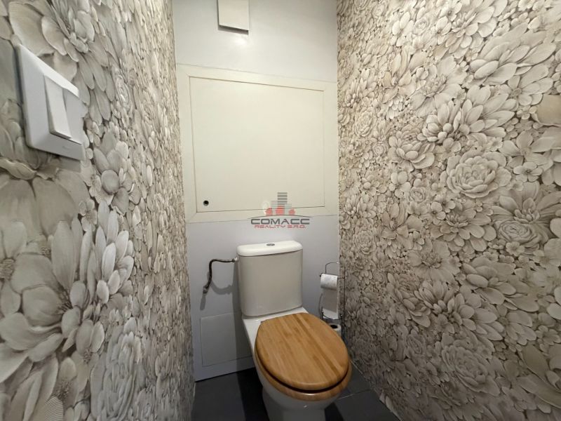 Toilette mit Blumen-Tapeten und einem Holzsitz in einer 3-Zimmer-Wohnung.