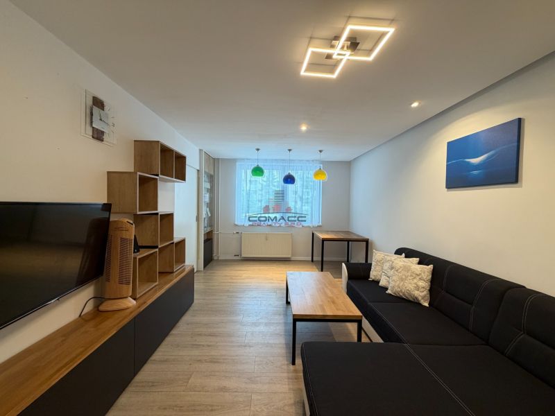 Wohnzimmer in einer 3-Zimmer-Wohnung mit Holzboden, bequemer Couch und Stauraum.