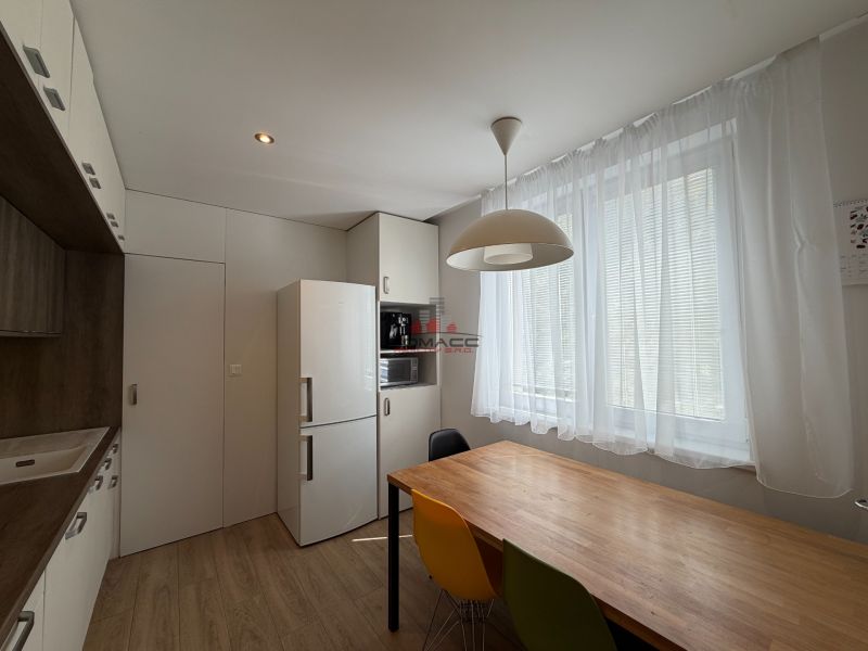 Küche mit weißem Kühlschrank, bunten Stühlen und Holzboden in einer 3-Zimmer-Wohnung.