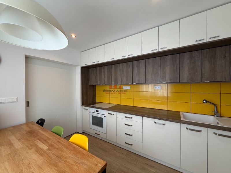 Küche in einer 3-Zimmer-Wohnung mit weißen Oberschränken und gelben Fliesen.