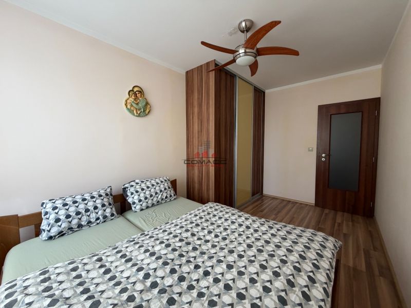 Schlafzimmer in einer 3-Zimmer-Wohnung mit Doppelbett, Einbauschrank und Boden mit Holzdekor.