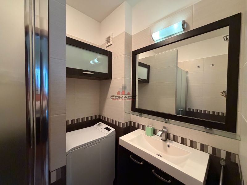 Badezimmer mit Waschbecken, Spiegel, Duschkabine und Waschmaschine in einer 3-Zimmer-Wohnung.