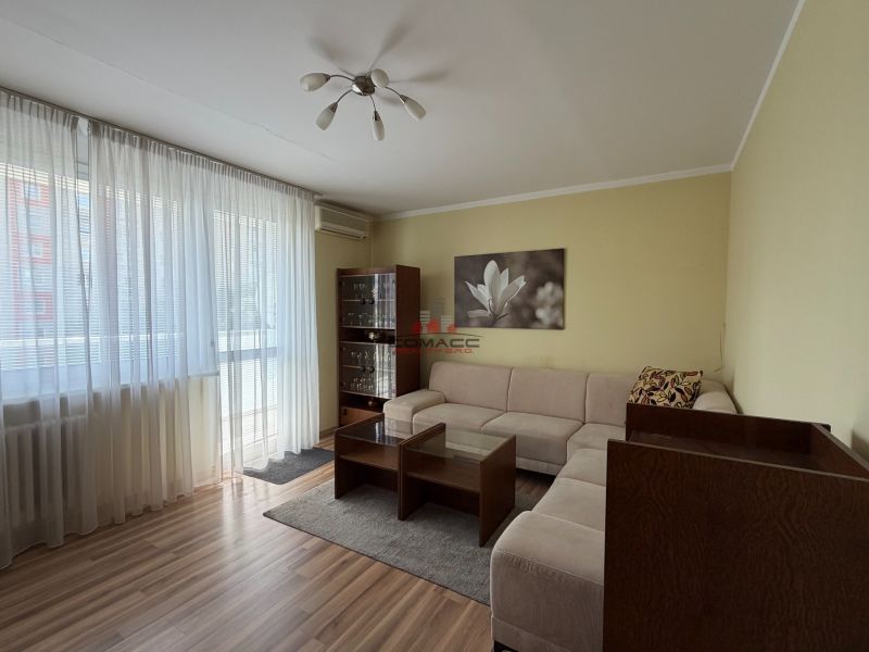 Wohnzimmer in einer 3-Zimmer-Wohnung mit einem Sofa und einem Boden in Holzoptik.
