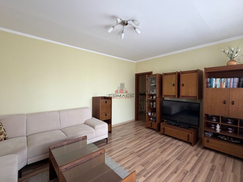 Wohnzimmer in einer 3-Zimmer-Wohnung mit Holzboden und Möbeln.