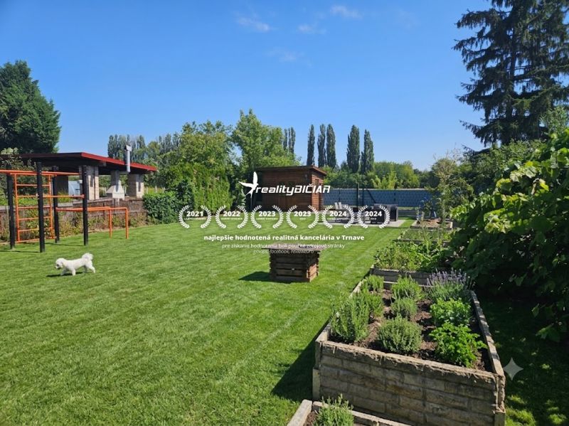 Garten in Kamenný Mlyn, Trnava mit grünem Rasen und Hochbeeten.