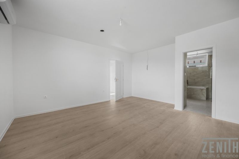 Ein ausdrucksloses Zimmer in einem Einfamilienhaus mit Holzboden und weißen Wänden.