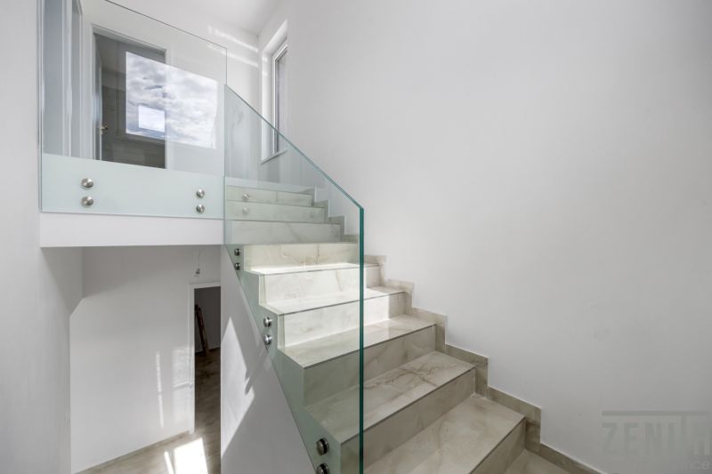 Glasgeländer mit Treppe im Einfamilienhaus, heller Raum, schlichtes Design.