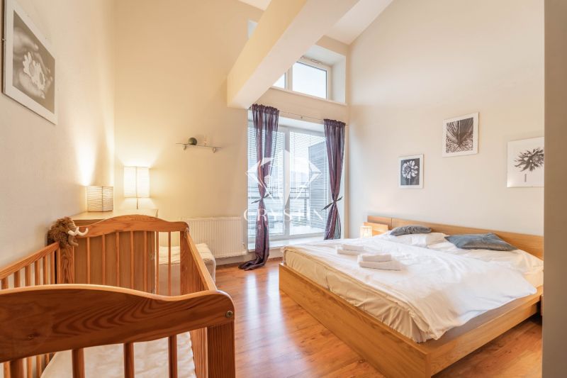 Helles Schlafzimmer im Ferienapartment mit Kinderbett und Holzboden.