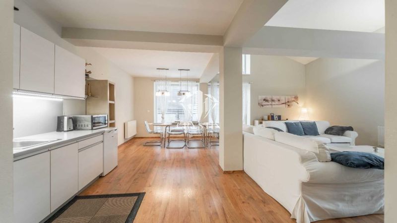 Ferienwohnung mit Holzboden, Küche, Esstisch und bequemen Sitzgelegenheiten.