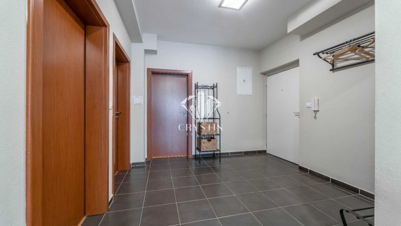 Eingangsbereich einer Ferienwohnung mit dunklen Fliesen, Holztüren und Garderobe.