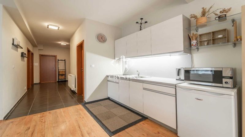 Kochnische mit Küchenzeile und Mikrowelle, Holzboden in einer Ferienwohnung.