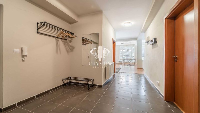 Der Flur des Ferienapartments mit Fliesen, einem Spiegel und einer Garderobenwand.