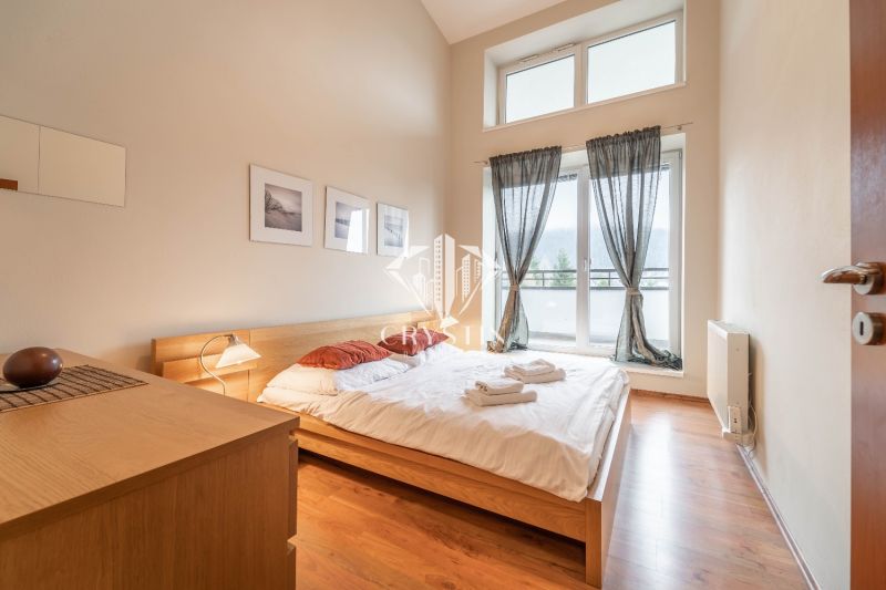 Helles Schlafzimmer mit Doppelbett und Holzboden in einer Ferienwohnung.