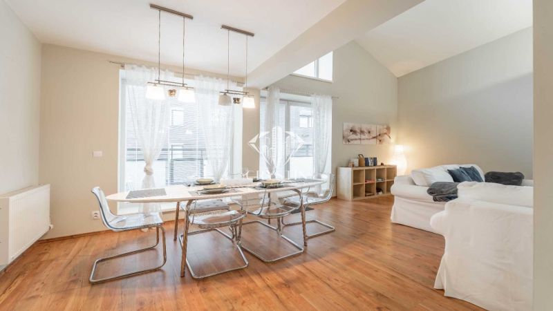 Ferienwohnung mit Esstisch, bequemen Sofas und einem Boden in Holzoptik.