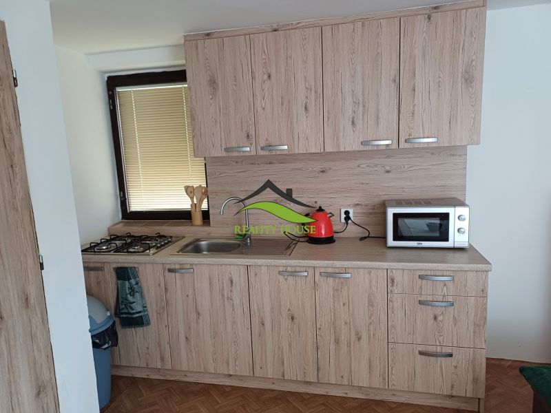 Küche mit Holzboden, Schränke mit Holzdekor und Geräte.