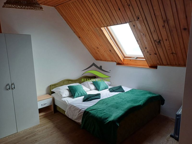 Ein Dachzimmer in einer Hütte mit einem Doppelbett und einem Dachfenster.