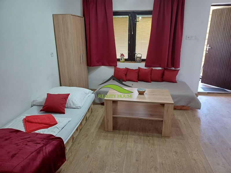 Ein Innenfoto einer Hütte mit einem Bett, einem Tisch und roten Accessoires.