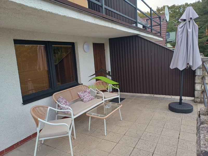 Terrasse der Hütte in Kaluža mit Sitzgelegenheiten und Sonnenschirm.