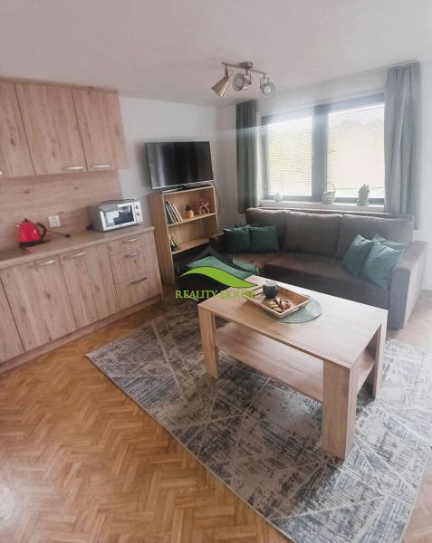 Wohnzimmer in der Hütte mit Holzboden, Sitzgarnitur und Tisch.