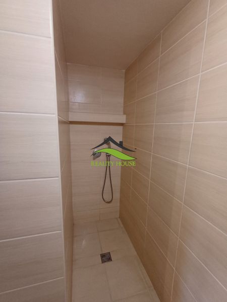 Badezimmer mit barrierefreier Dusche und hellen Keramikfliesen in der Hütte.