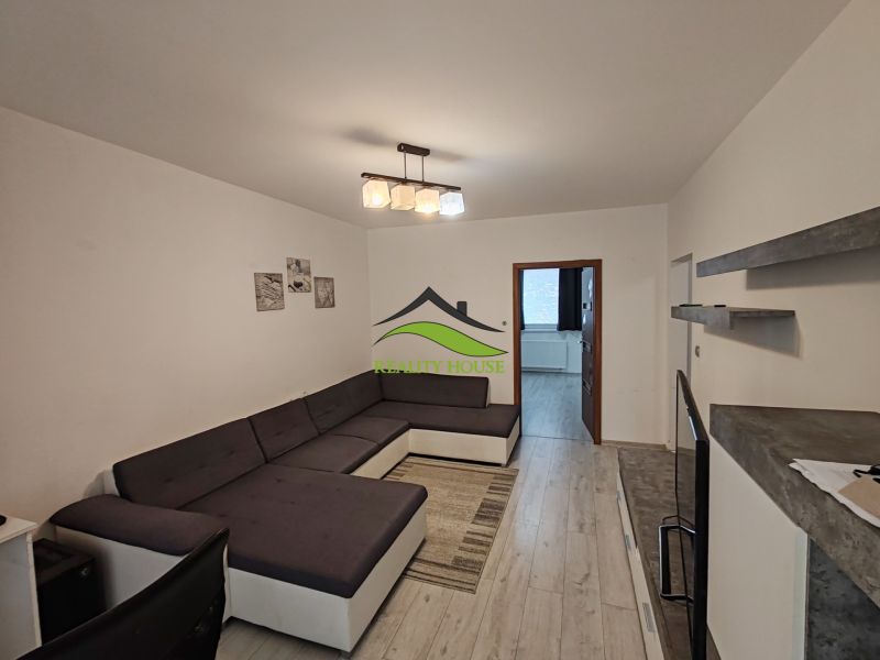 Wohnzimmer mit großem Sofa, Holzboden und schlichtem Interieur in einer 3-Zimmer-Wohnung.