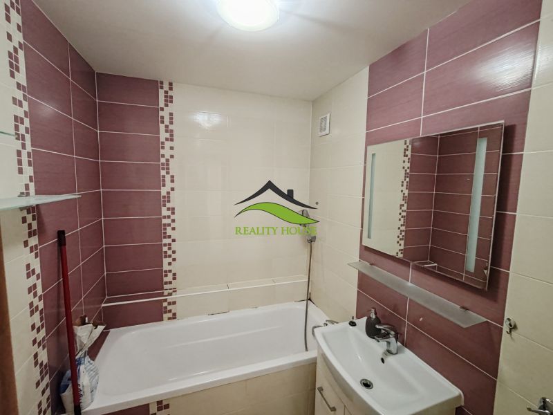 Badezimmer in einer 3-Zimmer-Wohnung mit Badewanne, Waschbecken und lila Fliesen.